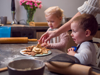 Mom, daughter, and son gather in modern kitchen, baking and decorating christmas cookies. Laughter fills air as they bond over christmas cookies, creating festive treats and family memories 