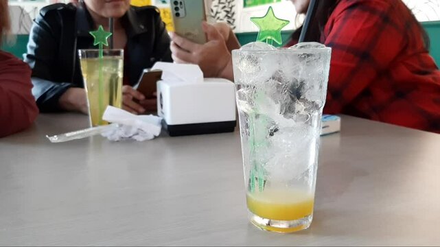 Frosted Glass of Cold Yellow Lemon Squash Soda With Ice Syrup Stirrer Condensation Droplets On Table During Restaurant Gathering Refreshing Drink Celebration Party Dining Scene Perfect for Birthday