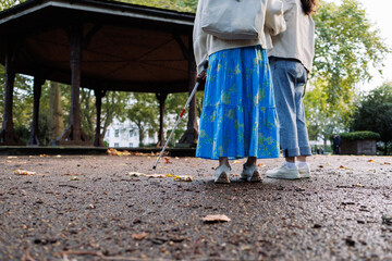Blind woman using white cane walking in park with friend