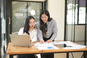Fototapeta premium Happy Asian business people working together using laptop and tablet in office.