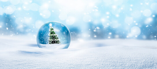 Weihnachtskugel aus Glas vor verschneiter Landschaft im Hintergrund