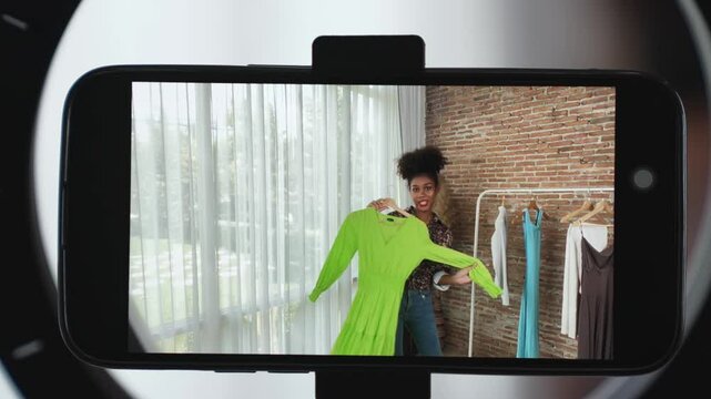 Rear view behide smartphone screen recording woman influencer shoot live stream vlog video review clothe crucial social media or blog. Girl with apparel studio lighting for marketing broadcast online