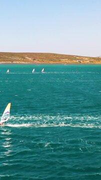 Vertical video of windsurfers - high quality aerial shot with drone of surfers windsurfing on Izmir beach in Aegean Sea Turkey Izmir