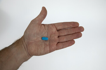 Single blue pill with the numbering 124 on in a caucasian male hand that is opened.  Concept for daily medication use.  White background. 