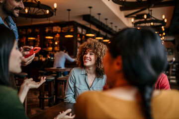A waiter taking orders at a restaurant from a group of multiracial friends.