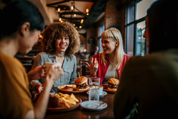 Young happy people having lunch together. An unrecognizable man passing burgers to his female friend.