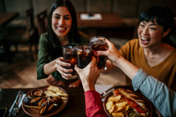 Four Young Female Friends Meeting For Drinks And Food Making A Toast In Restaurant