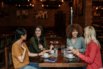 Young friends having a great time in restaurant. Multiracial group of young people sitting in a...