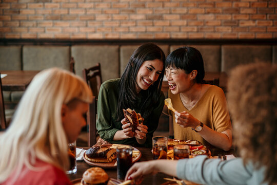 Young friends having a great time in restaurant. Multiracial group of young people sitting in a restaurant and smiling.