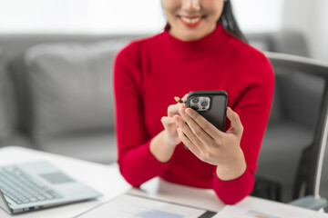 A businesswoman sits at her desk, smiling while talking on the phone and looking at her laptop. She focuses on analyzing tasks, planning strategies, and engaging in productive online discussions.
