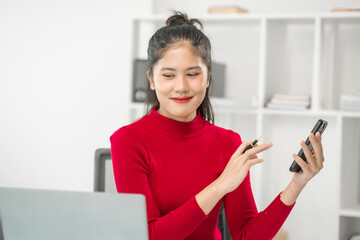 A businesswoman sits at her desk, smiling while talking on the phone and looking at her laptop. She focuses on analyzing tasks, planning strategies, and engaging in productive online discussions.