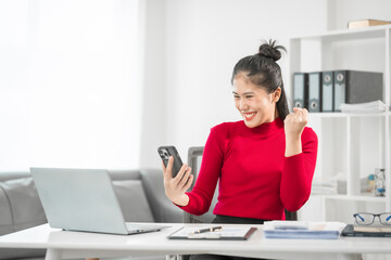 A businesswoman sits at her desk, smiling while talking on the phone and looking at her laptop. She focuses on analyzing tasks, planning strategies, and engaging in productive online discussions.