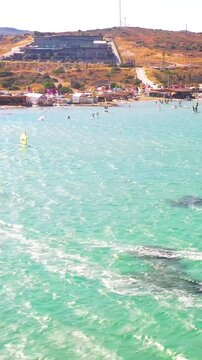 Vertical video of windsurfers - high quality aerial shot with drone of surfers windsurfing on Izmir beach in Aegean Sea Turkey Izmir