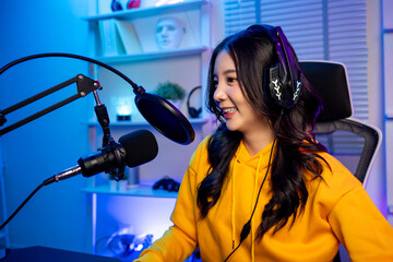 Asian audio DJ woman talking on microphone to broadcasting in neon room.
