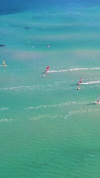 Vertical video of windsurfers - high quality aerial shot with drone of surfers windsurfing on Izmir beach in Aegean Sea Turkey Izmir