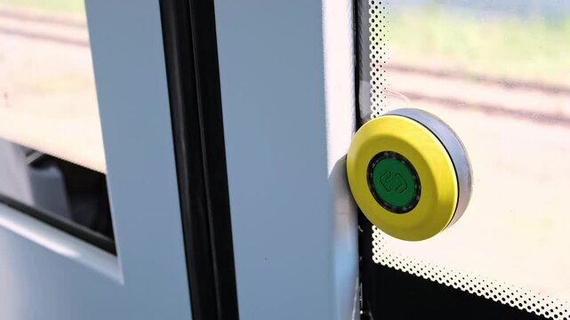 Open door button in subway car of the green and yellow colors on the window glass of a train during daytime traffic. The exit. The concept of getting out of any difficult situation. HQ 4K footage