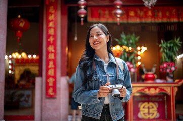 An attractive Asian female tourist visits a stunning Chinese shrine, enjoying her solo travels.