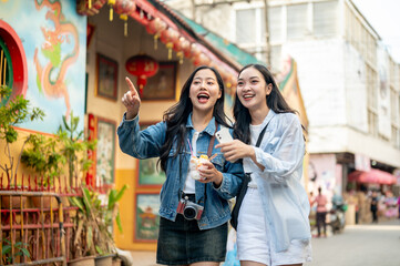 Two joyful young Asian female tourists explore the city in Thailand together, finding their location