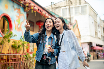 Two joyful young Asian female tourists explore the city in Thailand together, finding their location
