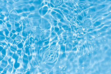 Blue water with ripples on the surface. Defocus blurred transparent blue colored clear calm water surface texture with splashes and bubbles. Water waves with shining pattern texture background.