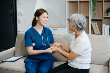 Asian caregiver doctor examine older patient woman therapist nurse at nursing home taking care of...
