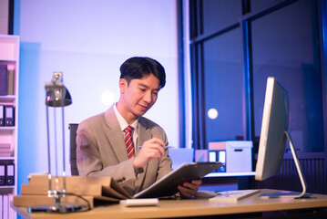 Businessman drinking coffee to get some energy for working overtime sitting at desk using computer and doing overtime