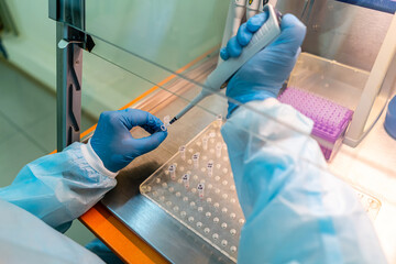 Scientist conducting experiments in a lab setting. A researcher wearing gloves and a lab coat is...