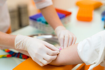 Patient receiving blood test in clinic. A healthcare worker is taking a blood sample from a...