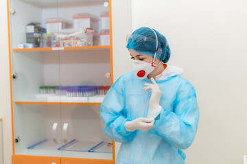 Health pro readying for lab care. A healthcare worker puts on gloves and adjusts protective gear,...