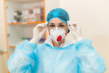 Healthcare worker in protective gear. A healthcare worker adjusts their protective mask and goggles, readying for medical tasks in a clinical setting.