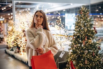 Holding bags. New year shopping and presents. Woman is near the Christmas tree