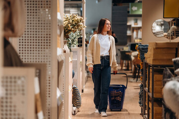 Blue basket is on the floor. Woman is in the shop with decoration, indoors