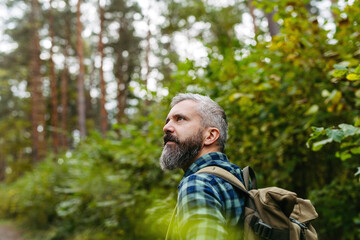Handsome man standing in the middle of nature, enjoying peaceful atmosphere of the forest,...