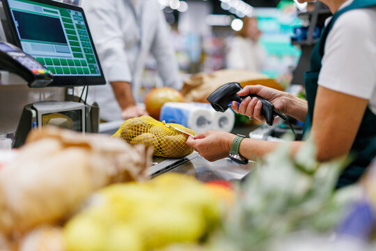 Cashier scanning potatoes at supermarket checkout counter