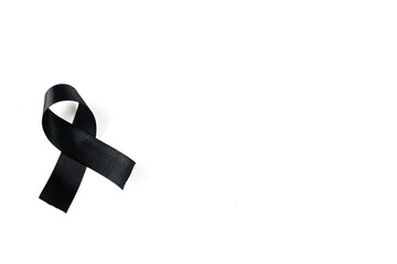 A black ribbon on a white background as a symbol of sadness, mourning or cancer awareness.