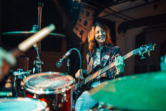 Female bass guitarist performing live on stage with drummer - Powered by Adobe