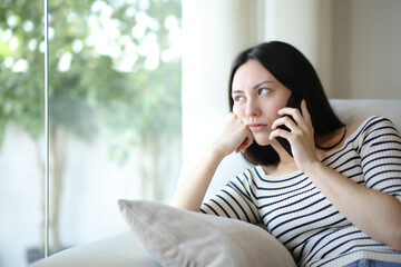 Bored asian woman waiting in a phone conversation at home