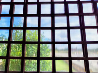 Window grilles framing a view of lush greenery and a cloudy sky during the daytime, capturing an outdoor essence