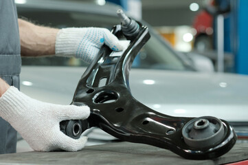 New car parts. An auto mechanic is preparing to replace the right arm of the car's front...