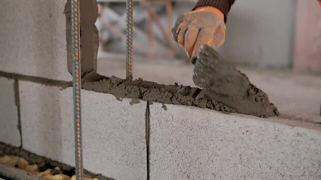 Construction worker applying cement between bricks on a construction site, ensuring precision and quality in the masonry work