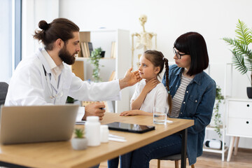 Young Caucasian girl with mother at doctor's office during medical consultation. Female doctor...