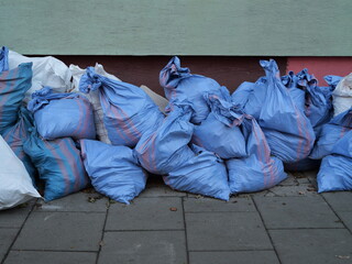 Construction debris bags stacked on a city sidewalk during renovation. Urban waste and building materials collected in colorful sacks