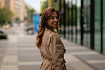 Fototapeta premium Close-up of an attractive woman wearing trench coat and walking on the street