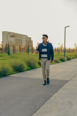 Fototapeta premium A man in a blue jacket and striped shirt walks down a sidewalk