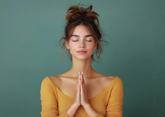 Young beautiful woman model meditates and prays. Sitting in a yoga position. Nature green background.