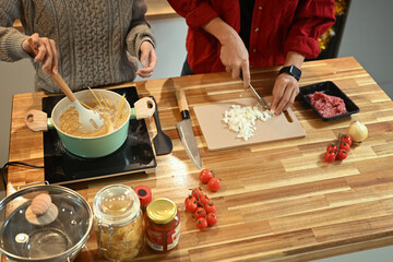 Young couple preparing a tasty pasta dish with fresh ingredients on the wooden countertop