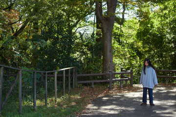 秋の公園で一人で散歩する小学生の女の子の様子
