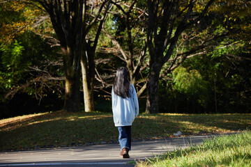 秋の公園で一人で散歩する小学生の女の子の様子