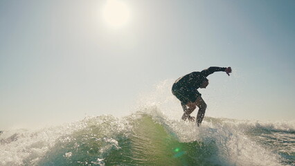 Sportsman performs tricks while balancing on a wakeboard. Wakeboarding behind a motorboat on the...