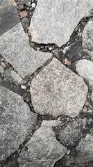 Obraz premium Close-up view of rough stone pavement with various shapes and textures. Ideal for backgrounds or natural design elements.